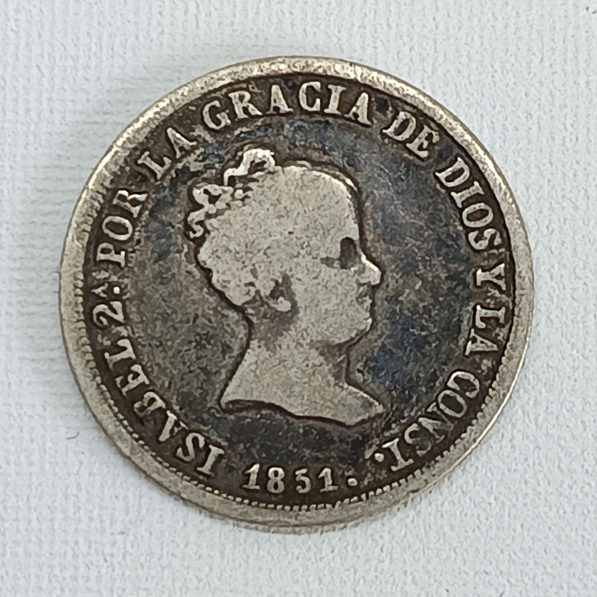 La pièce de 2 Reales de 1851 d'Espagne, frappée sous le règne de la reine Isabelle II, est une pièce de monnaie en argent d'une grande valeur historique. Caractéristiques de la pièce : * Règne : Reine Isabelle II (1833-1868) * Date : 1851 * Dénomination : 2 Reales * Composition : Argent (généralement 0.812 de pureté) * Poids : Environ 2,45 à 3 grammes * Diamètre : Autour de 18 mm * Atelier de frappe : Ces pièces ont été frappées dans divers ateliers espagnols. La marque d'atelier "S" indique qu'elle a été frappée à Séville.