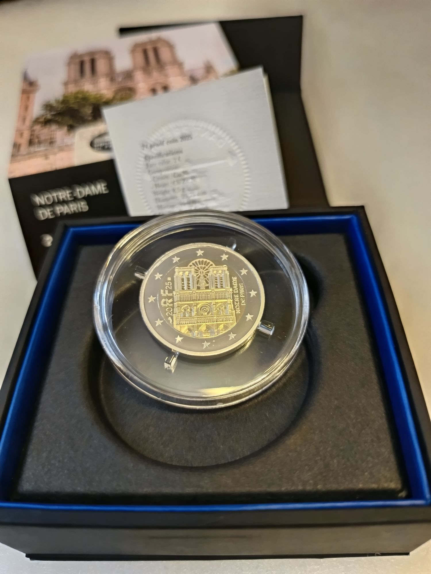 Le descriptif concerne la pièce commémorative de 2 euros "Notre-Dame de Paris" (France, 2025) en qualité Belle Épreuve (BE) : * Qualité BE : C'est la plus haute qualité numismatique, caractérisée par un fond poli miroir et des reliefs mats. * Dessin : La face nationale représente une mise en volume détaillée de la façade ouest de la cathédrale, avec sa rosace et ses deux tours. * Caractéristiques : Bi-métallique, diamètre de 25,75 mm, poids de 8,5 g, valeur faciale de 2 euros. * Tirage : Le tirage est très limité, généralement de 15 000 exemplaires pour cette qualité. * Présentation : Elle est vendue sous capsule dans son coffret d'origine Monnaie de Paris avec un certificat d'authenticité. Elle commémore la réouverture au public de la cathédrale.